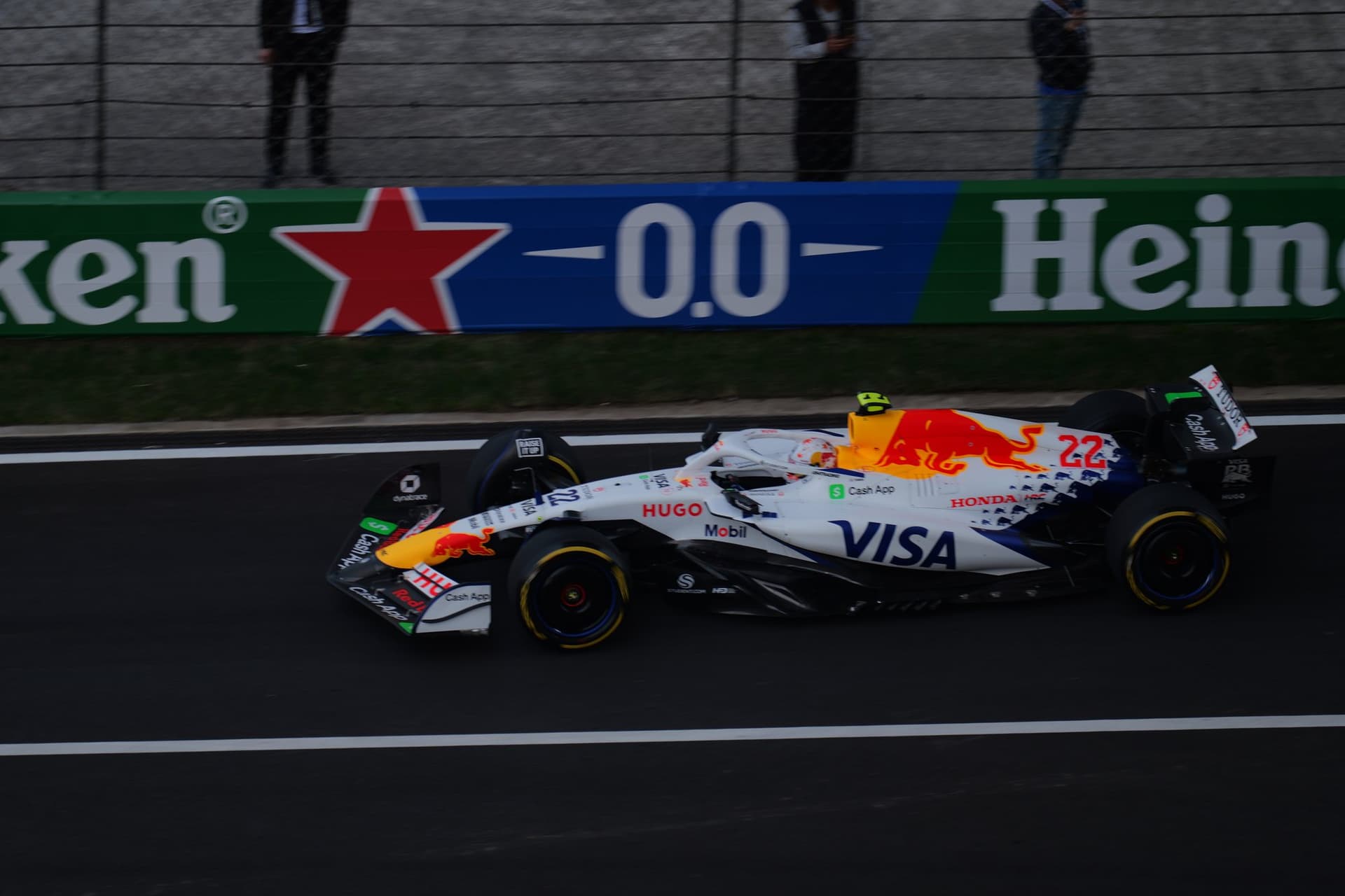 Formula One car moving along a race circuit with track signage in the background