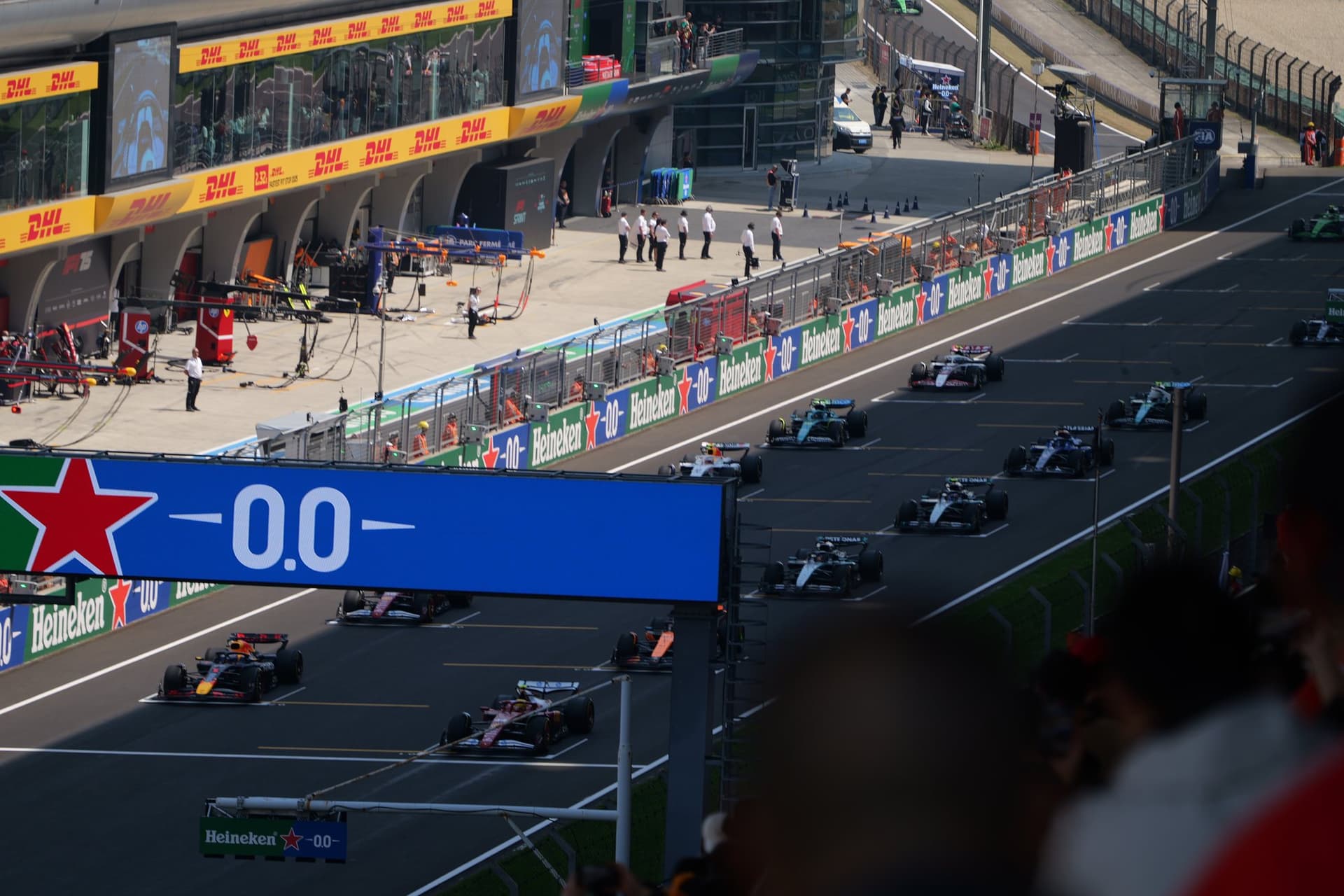 Formula One starting grid seen from above with teams, cars, pit lane, and race infrastructure